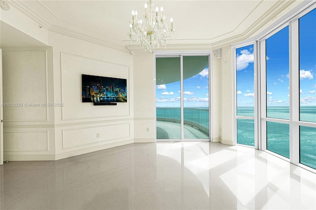 spare room featuring a healthy amount of sunlight, ornamental molding, a decorative wall, and a notable chandelier