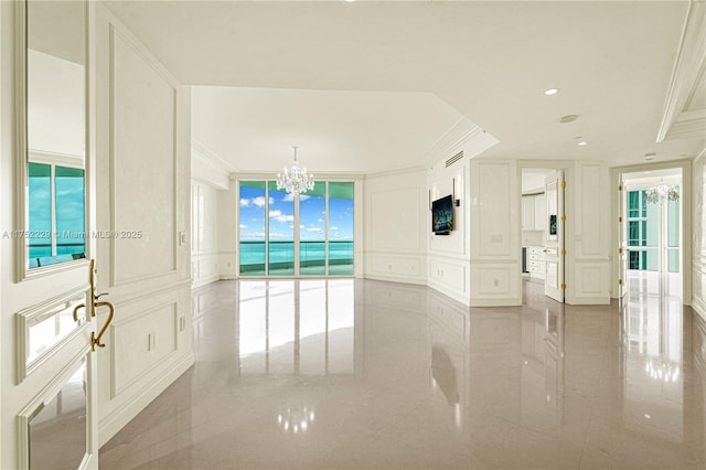 empty room featuring ornamental molding, marble finish floor, a decorative wall, a notable chandelier, and recessed lighting