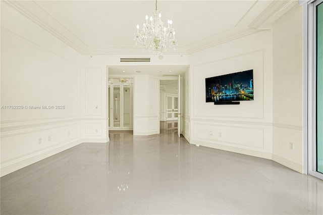 spare room featuring visible vents, ornamental molding, a decorative wall, and a chandelier