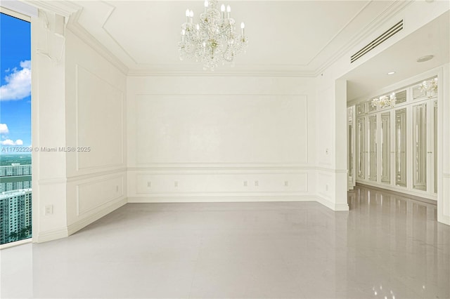 empty room with crown molding, a chandelier, visible vents, and a decorative wall