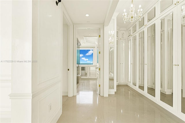 corridor featuring a chandelier, a decorative wall, and crown molding