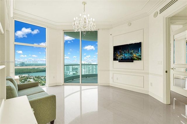 living area featuring ornamental molding, a chandelier, a decorative wall, and marble finish floor