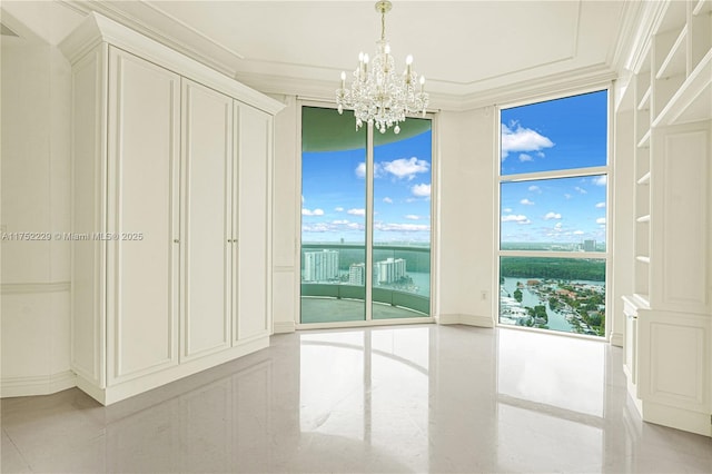 spare room featuring a wall of windows, a wealth of natural light, crown molding, and an inviting chandelier