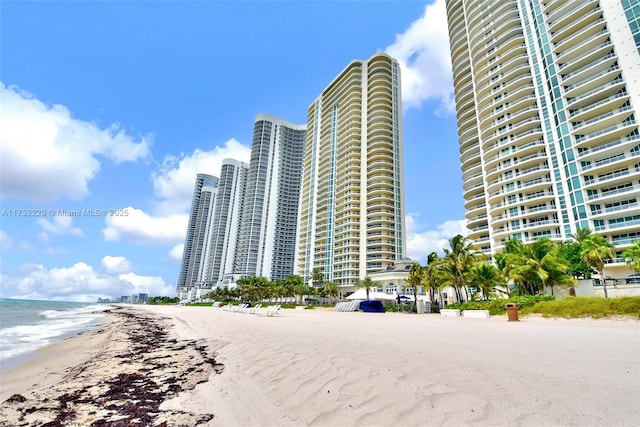 view of building exterior featuring a view of city, a water view, and a view of the beach