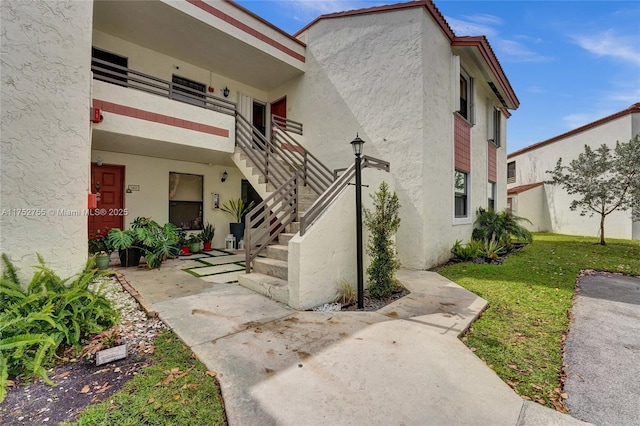 exterior space with a balcony, a lawn, and stucco siding