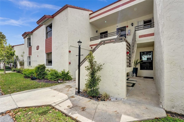 view of property exterior with a tile roof, a balcony, and stucco siding