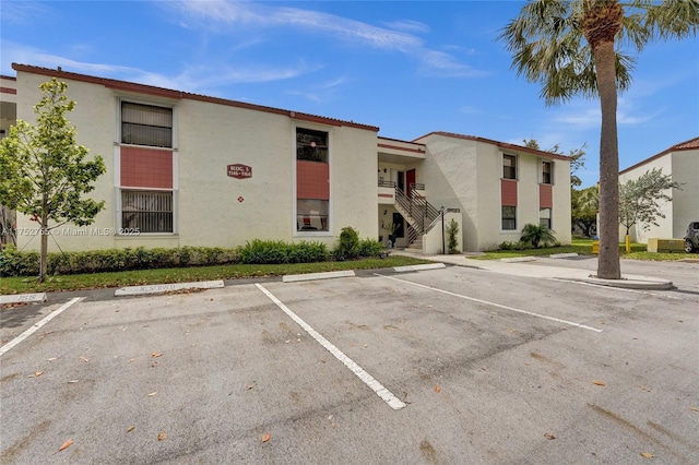 view of building exterior featuring stairs and uncovered parking