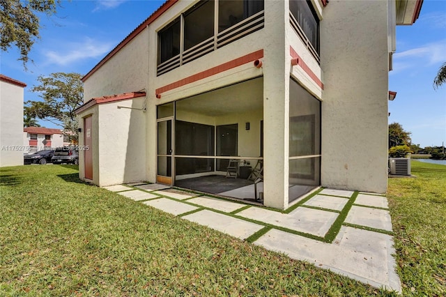 rear view of house with central air condition unit, a lawn, a patio area, and stucco siding