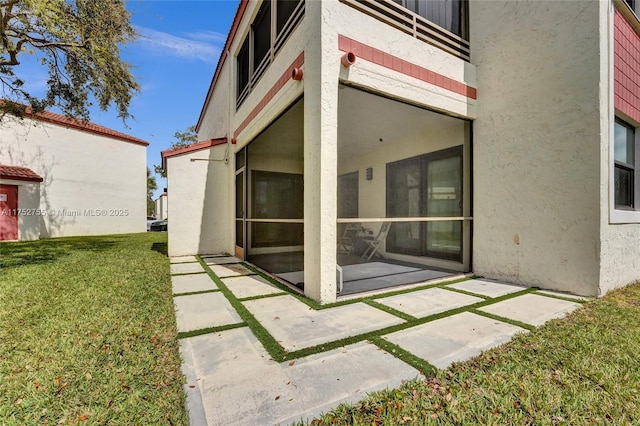 back of property with stucco siding, a lawn, and a patio