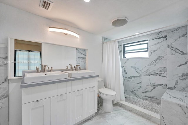 full bathroom with marble finish floor, tiled shower, a sink, and visible vents