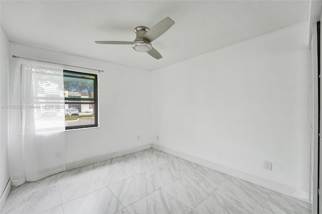 spare room featuring ceiling fan and baseboards