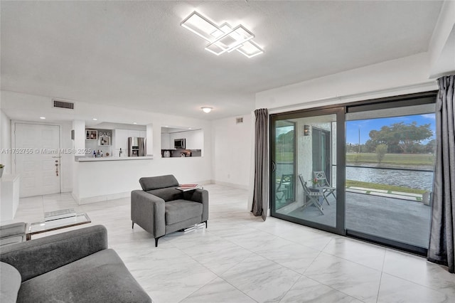 living area with a water view, baseboards, visible vents, and a textured ceiling