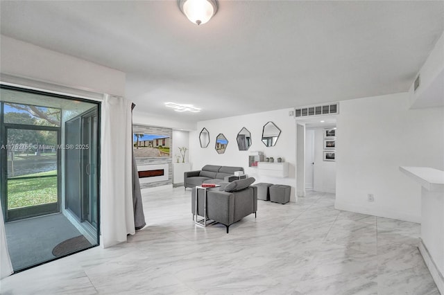 living area featuring a large fireplace, visible vents, and marble finish floor