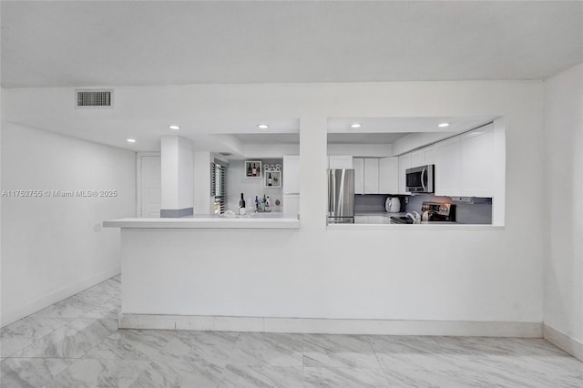 kitchen with stainless steel appliances, light countertops, visible vents, white cabinetry, and a peninsula