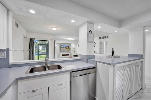 kitchen featuring visible vents, white cabinets, a sink, dishwasher, and a peninsula