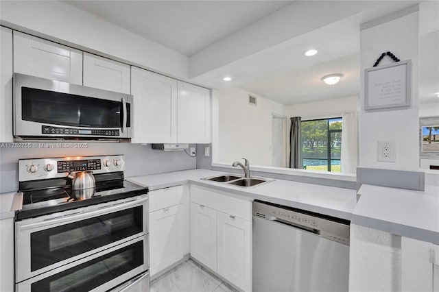 kitchen with light countertops, appliances with stainless steel finishes, a sink, and white cabinets