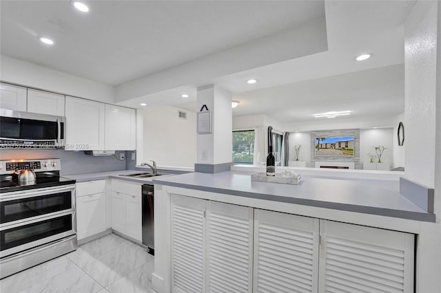 kitchen with white cabinetry, stainless steel appliances, a sink, and open floor plan