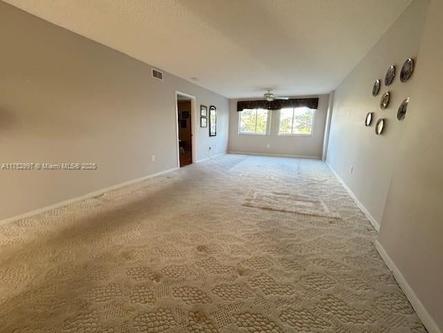 carpeted spare room featuring baseboards, visible vents, and a textured ceiling