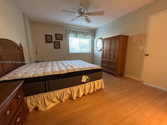 bedroom featuring baseboards, ceiling fan, light wood-style flooring, and a textured ceiling