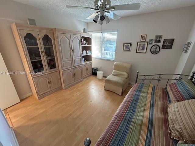 bedroom featuring a textured ceiling, light wood-type flooring, and a ceiling fan