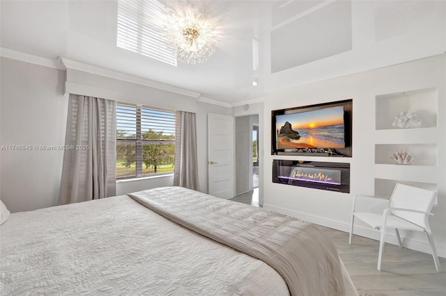 bedroom featuring light wood finished floors, ornamental molding, a glass covered fireplace, a chandelier, and baseboards