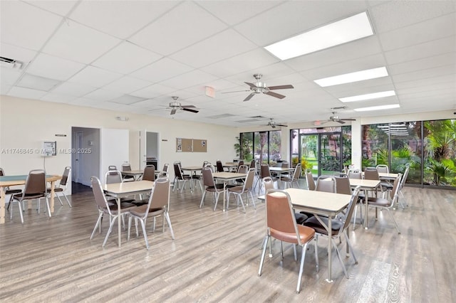 dining space with visible vents, a drop ceiling, and wood finished floors