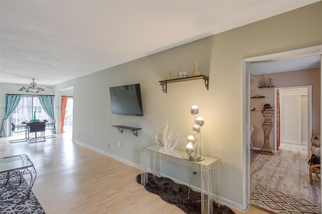 living room with baseboards, ceiling fan, and light wood finished floors