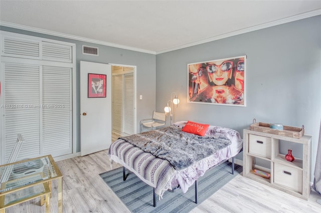 bedroom with ornamental molding, light wood finished floors, and visible vents