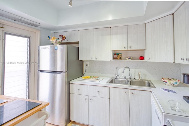 kitchen with a sink, light countertops, freestanding refrigerator, decorative backsplash, and open shelves