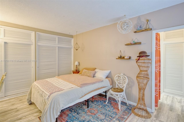 bedroom featuring light wood finished floors, baseboards, and a textured ceiling