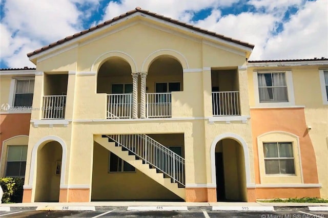 view of building exterior featuring stairs and uncovered parking