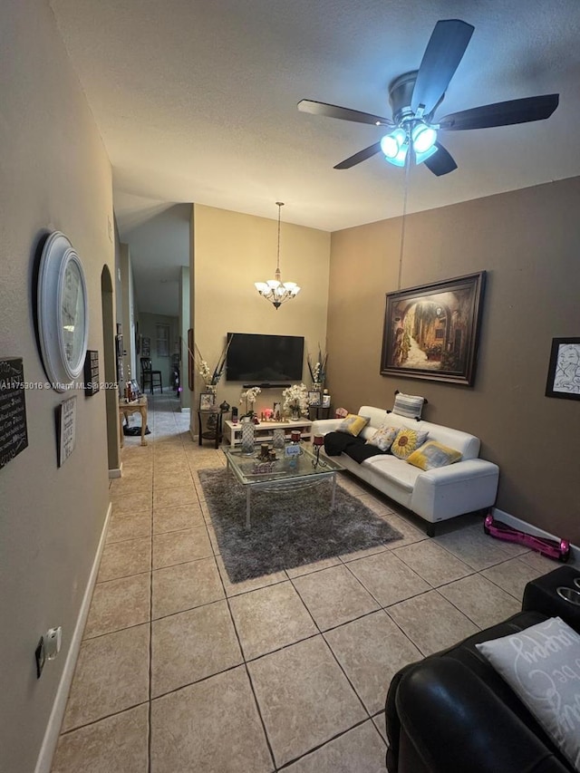 living room featuring light tile patterned floors, baseboards, vaulted ceiling, and ceiling fan with notable chandelier