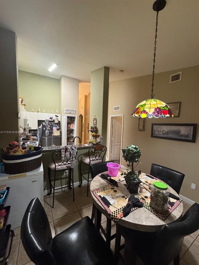 dining area featuring light tile patterned flooring, visible vents, and baseboards