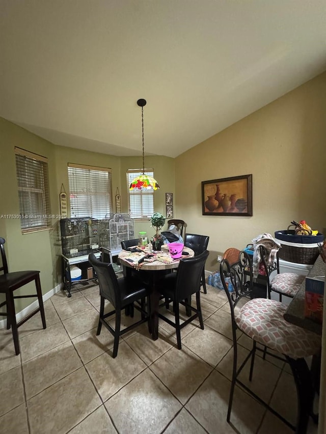 tiled dining room featuring vaulted ceiling and baseboards