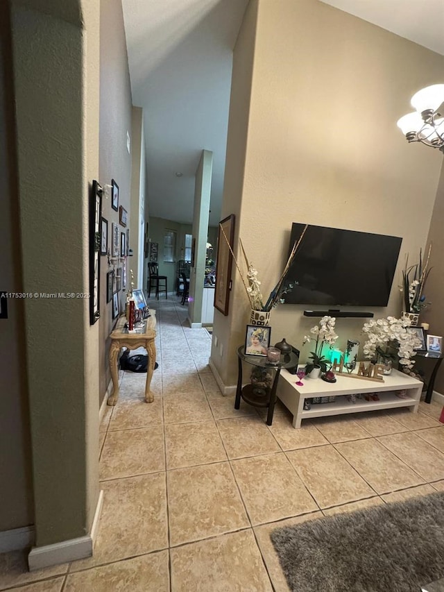 interior space featuring light tile patterned floors, high vaulted ceiling, a chandelier, and baseboards