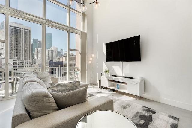 living room featuring an inviting chandelier, a high ceiling, and baseboards