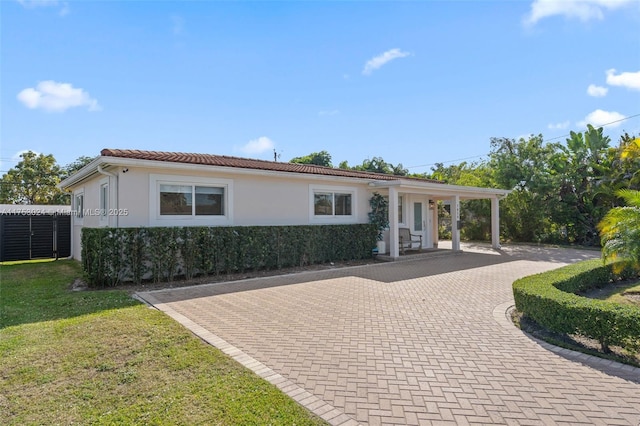 view of front of house featuring a tiled roof, a front yard, decorative driveway, and stucco siding