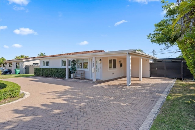 view of front of property with decorative driveway, fence, and stucco siding