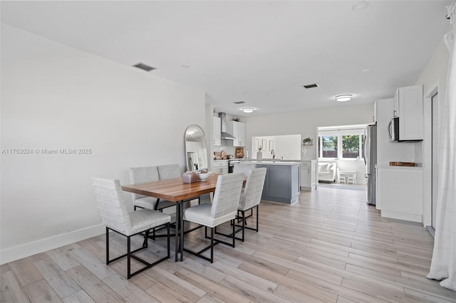 dining room with light wood-type flooring, baseboards, and visible vents