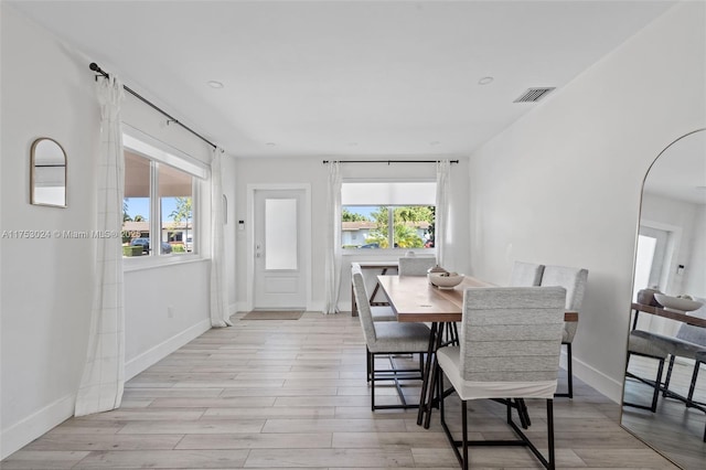 dining room featuring light wood-type flooring, baseboards, visible vents, and a wealth of natural light