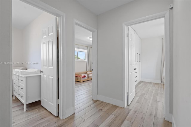 corridor featuring light wood-type flooring and baseboards