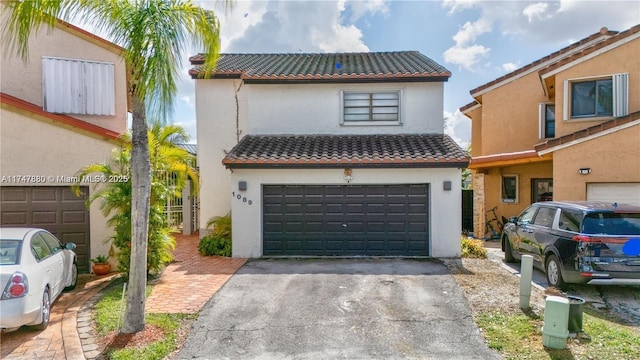 view of front of property featuring driveway, a tiled roof, an attached garage, and stucco siding