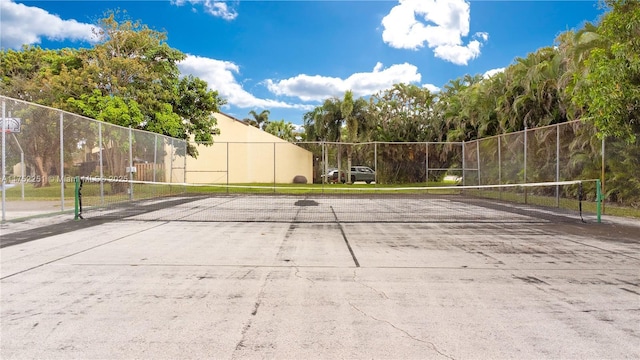 view of property's community featuring a tennis court and fence