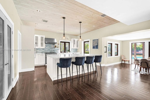 kitchen featuring hanging light fixtures, ventilation hood, glass insert cabinets, and white cabinetry