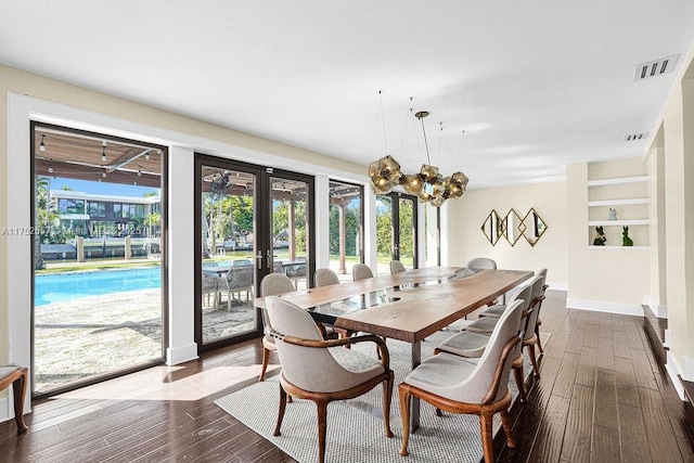 dining space featuring dark wood-type flooring, a wealth of natural light, visible vents, and an inviting chandelier