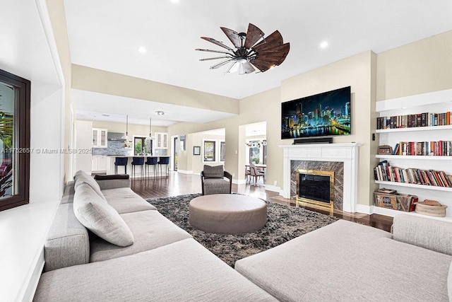 living area with a premium fireplace, recessed lighting, wood finished floors, and baseboards