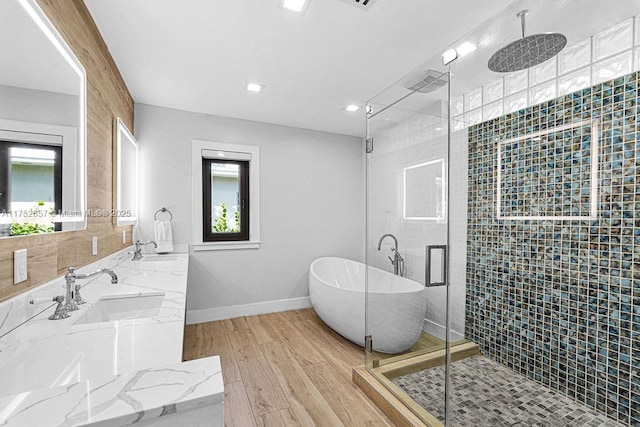 full bath featuring a freestanding bath, wood finished floors, a sink, and a wealth of natural light