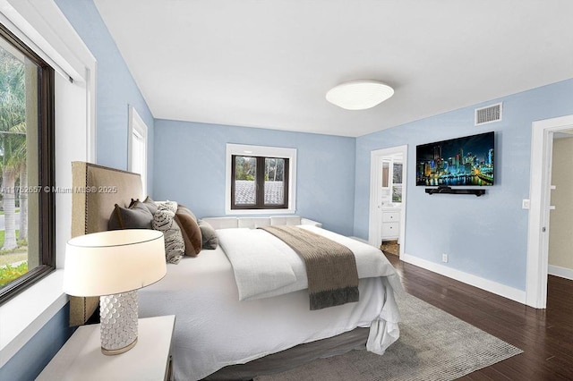 bedroom with dark wood-style floors, visible vents, connected bathroom, and baseboards