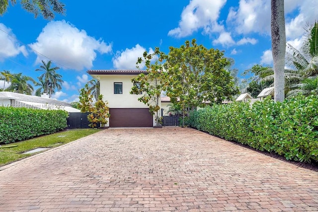 view of front of house with a garage, a tiled roof, decorative driveway, and stucco siding