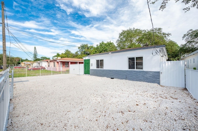 view of front of home featuring stone siding, fence, and stucco siding